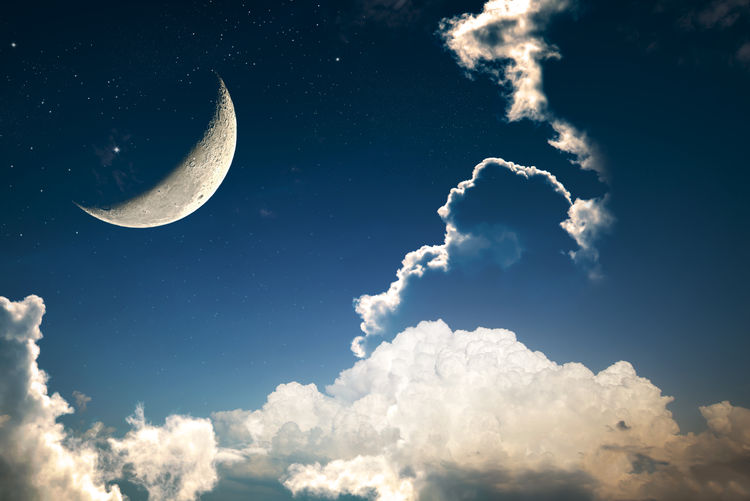 Low angle view of crescent moon in cloudy sky