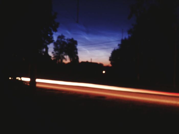 Silhouette of light trails on road at night