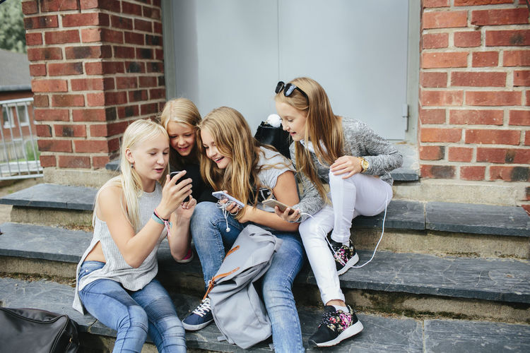 Girls sitting on steps and using cell phone