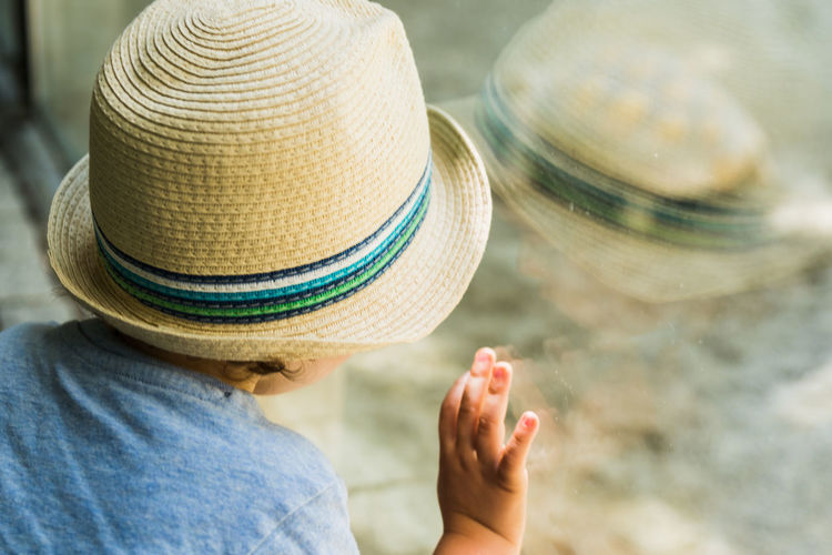 Close-up of boy with hat looking through window