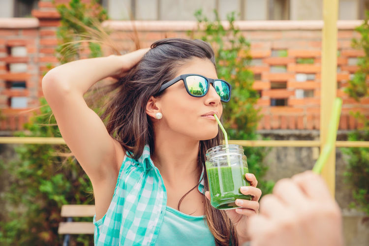 Woman in sunglasses drinking smoothie at restaurant