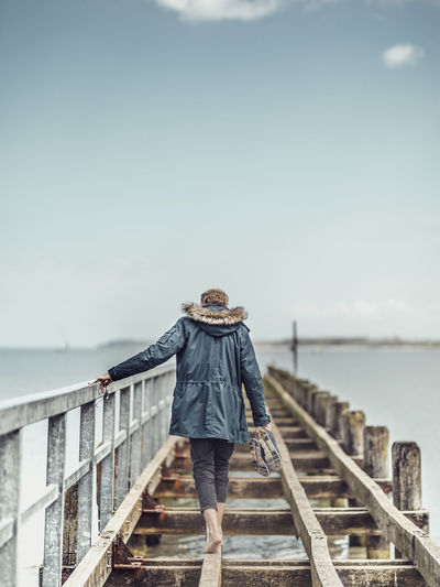 Rear view full length of man walking amidst sea on pier