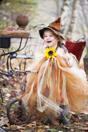 Laughing girl wearing witch hat on tricycle