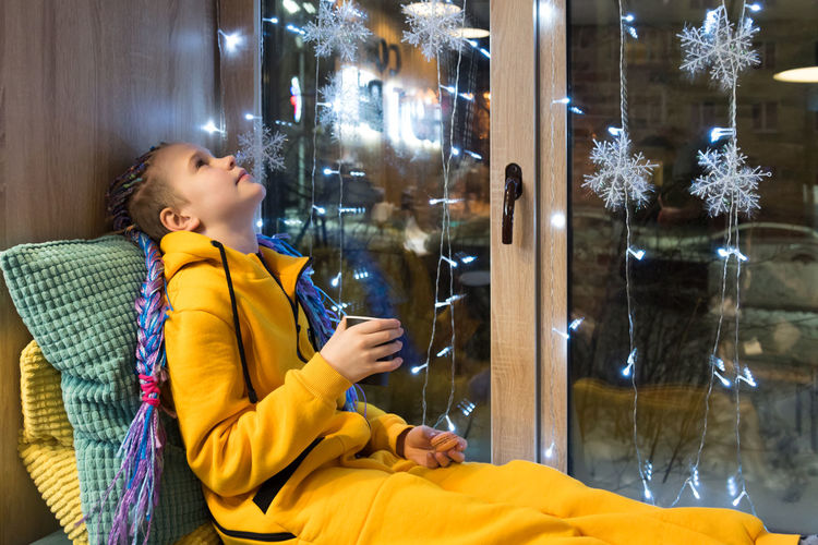 Side view of young woman using mobile phone at home