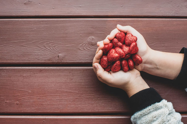 High angle view of hand holding strawberries on table