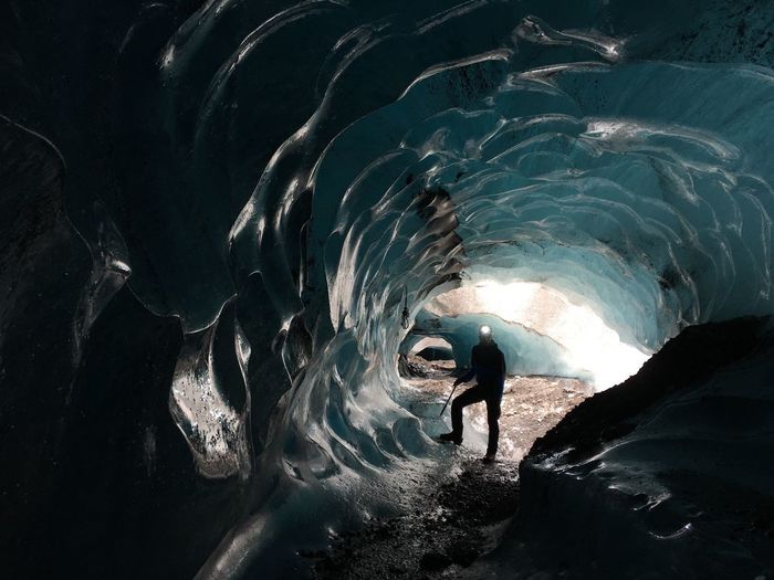 Silhouette male hiker standing in ice cave