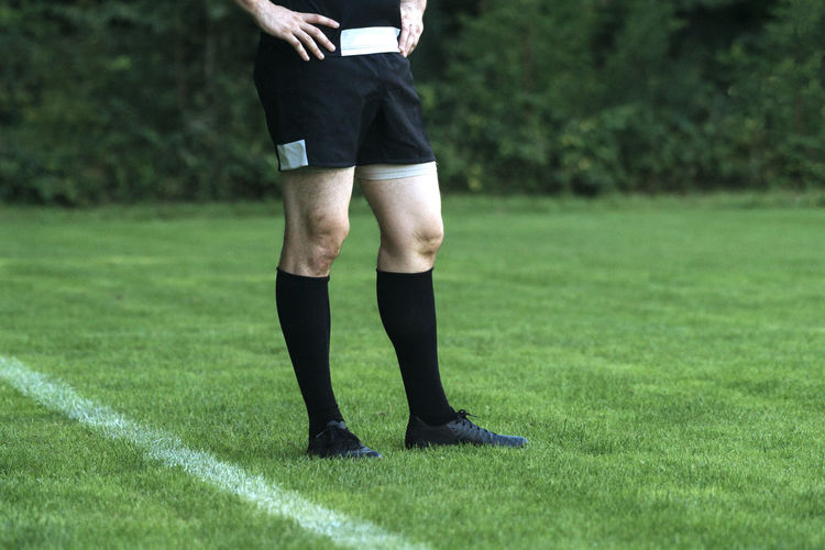 Low section of male rugby player standing on field