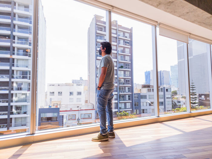 Young businessman looking through the windows in a big office