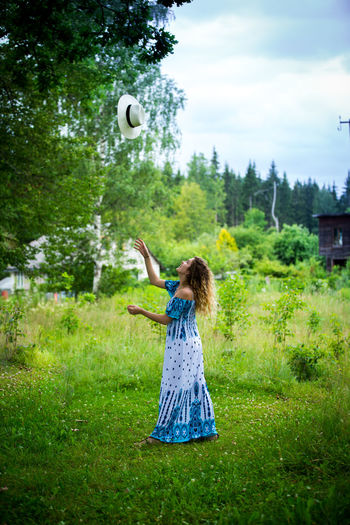 Woman playing with hat while standing on field