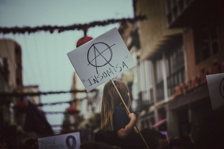 Low angle view of girl holding placard in city