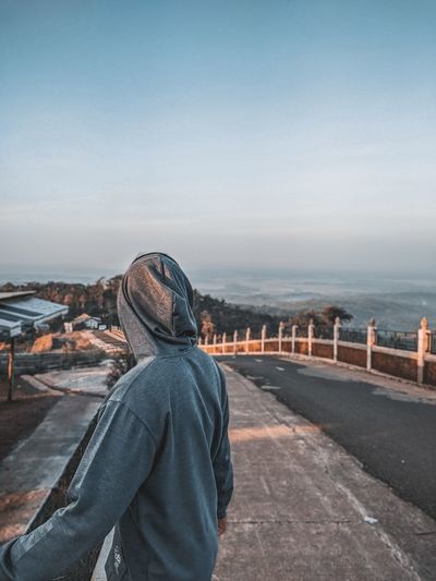 Rear view of man looking at sea against sky