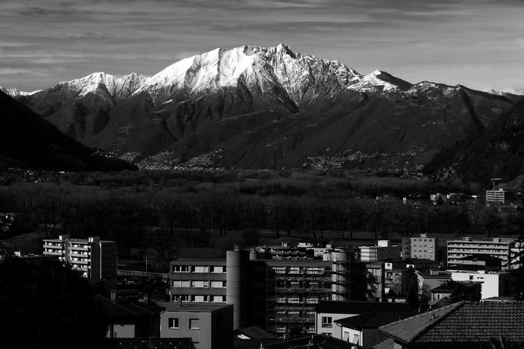 Aerial view of cityscape and mountains against sky