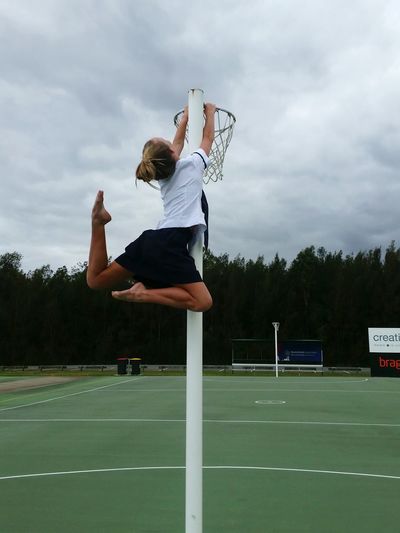 Teenage girl hanging on hoop