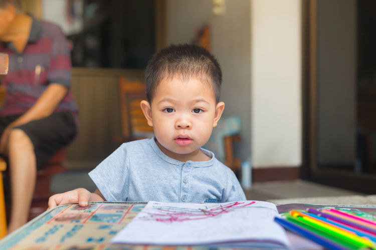 Portrait of boy drawing on table at home