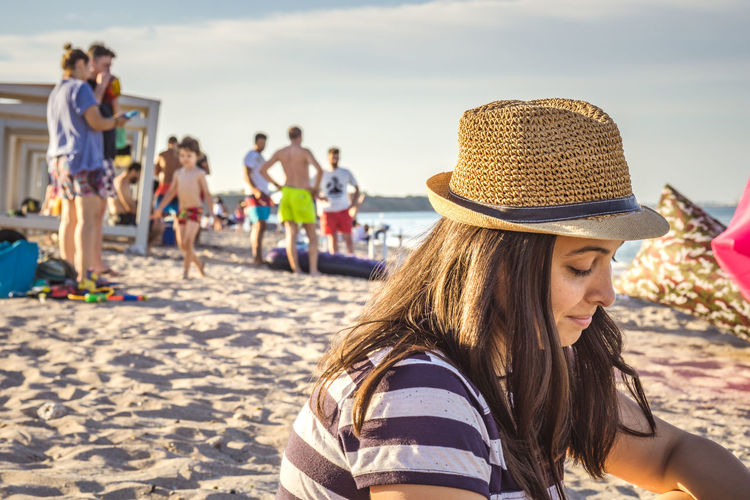 Woman wearing hat sitting at beach