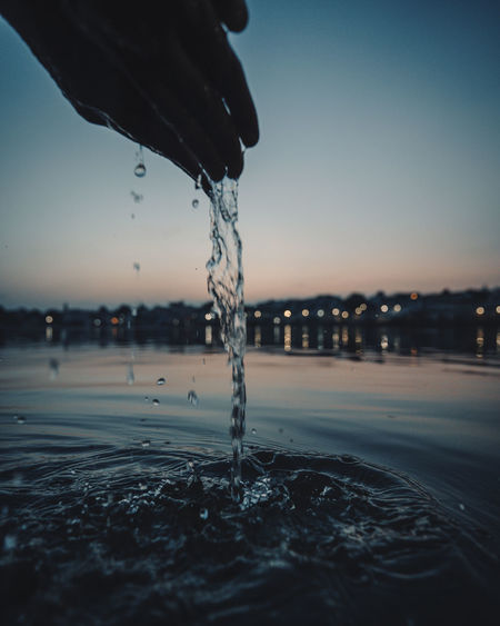 Close-up of hand splashing water against clear sky