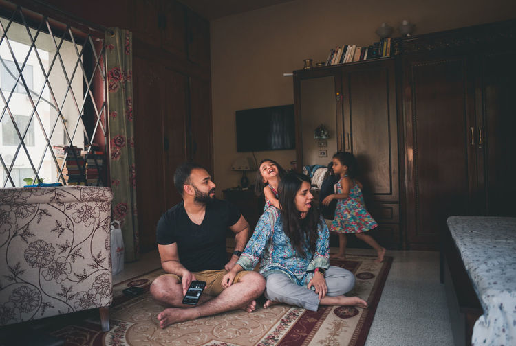 Parents with daughters on carpet in living room at home