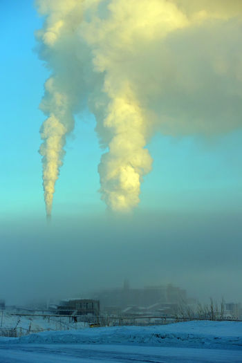 Aerial view of smoke stack against sky during winter