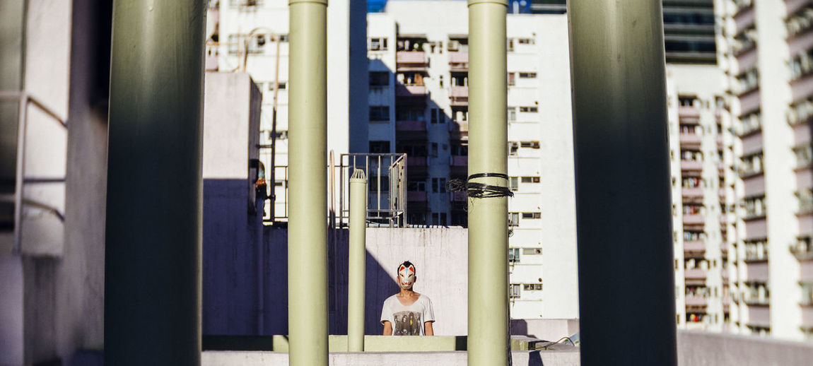 Man on building terrace seen through poles