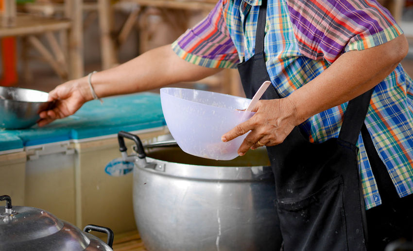 Midsection of women preparing food in kitchen at shop
