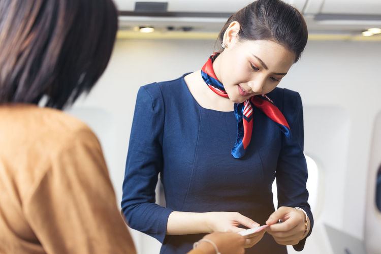 Cabin crew greeting and check flight information passenger in airplane person