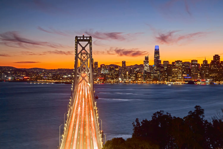 Illuminated buildings in city at sunset
