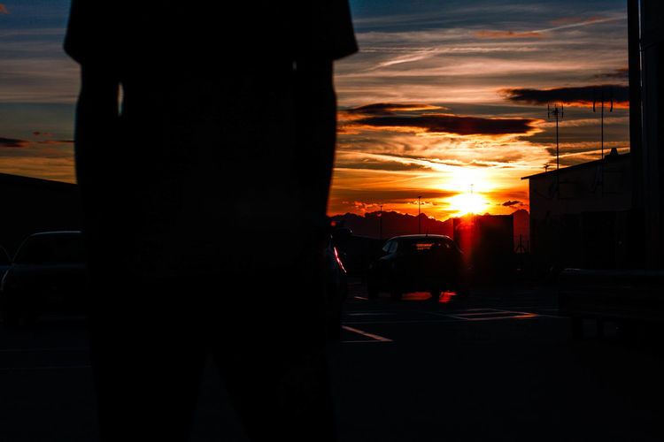 Silhouette man on street against sky during sunset