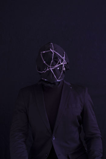 Man wearing mask against black background
