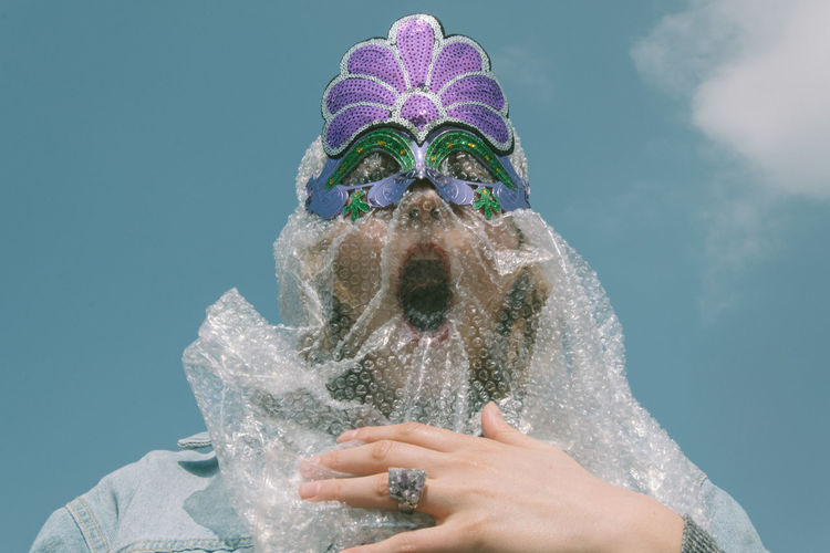 Low angle view of woman wearing eye mask against sky