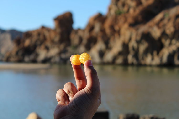 Close-up of hand holding chips against sea