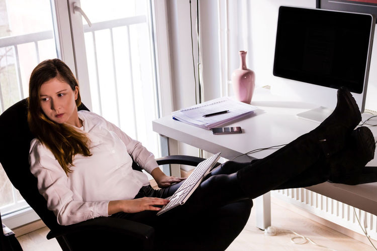 Full length of businesswoman reading paper on table in office