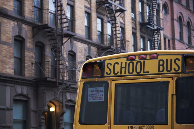 Traditional yellow school bus driving along street in new york city on cloudy day