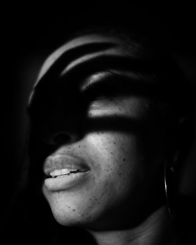 Close-up portrait of smiling young woman against black background