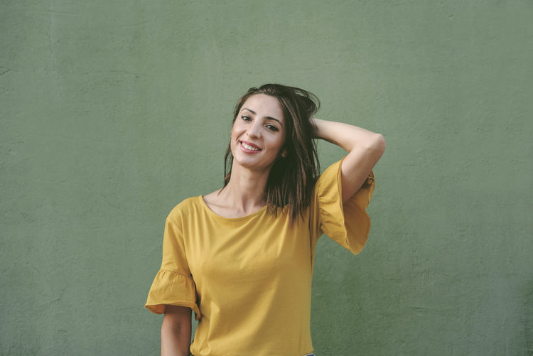 Portrait of a smiling young woman against yellow wall