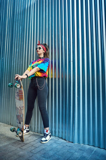 Young woman with urban style, she poses with a long board.