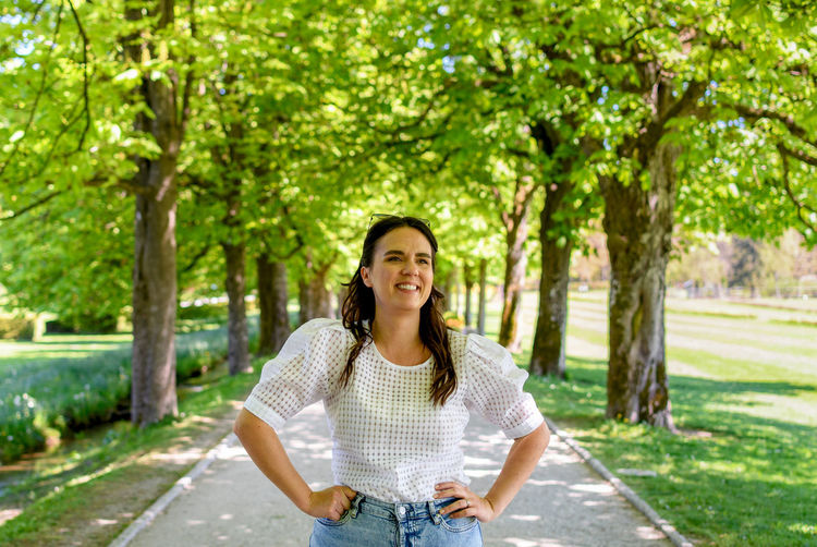 Portrait of beautiful young woman standing on path in park during spring.