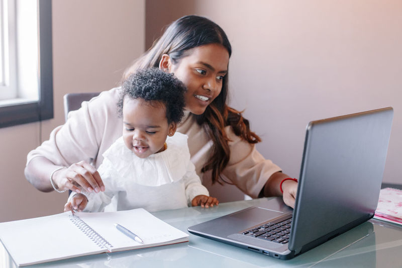 Mixed race indian mother with african black baby working online from home. workplace of freelancer. 