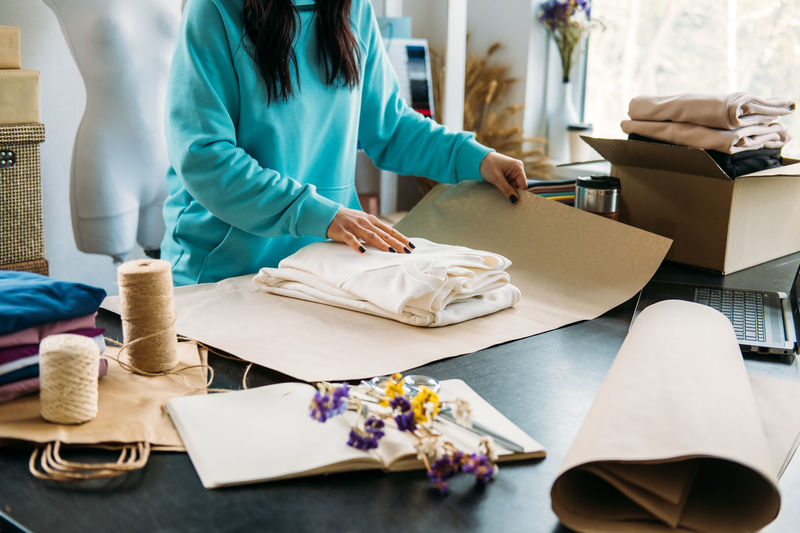 Small business owner woman packs the goods in eco packaging in office, shop.