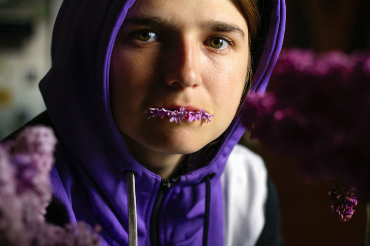 Young woman winh flower in her mouth. beautiful plump lips with a delicate lilac or very peri color.