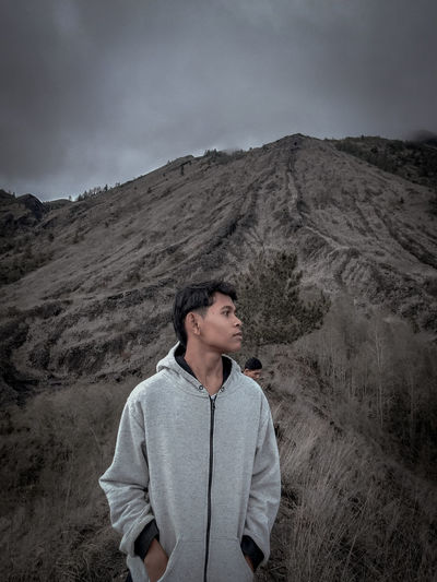 Young man standing against mountain