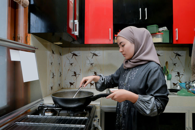Side view of woman preparing food in kitchen