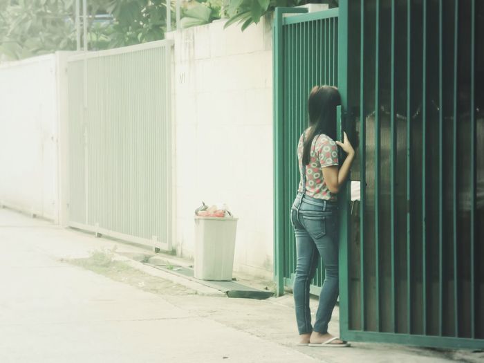 Rear view of woman standing by gate