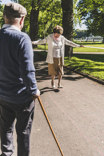 Senior woman playing hopscotch while husband watching her