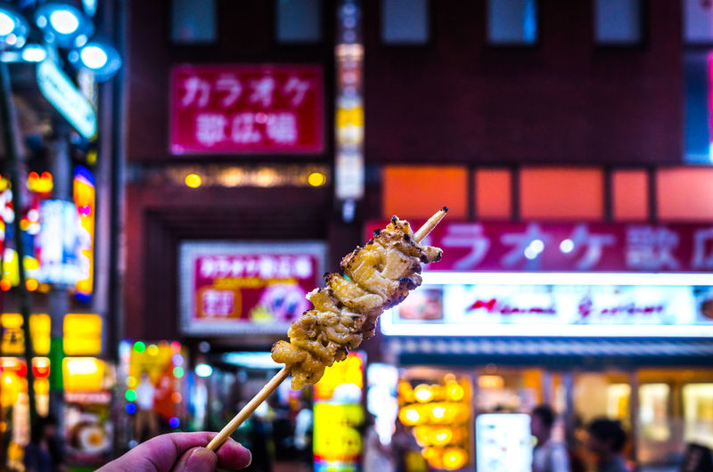 Cropped image of hand holding food on skewer at market