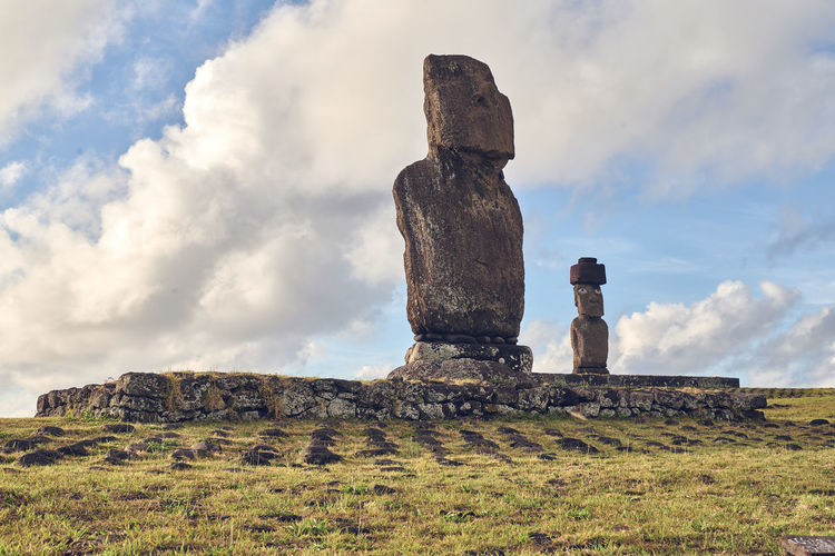 Low angle view of moai statues on field against sky