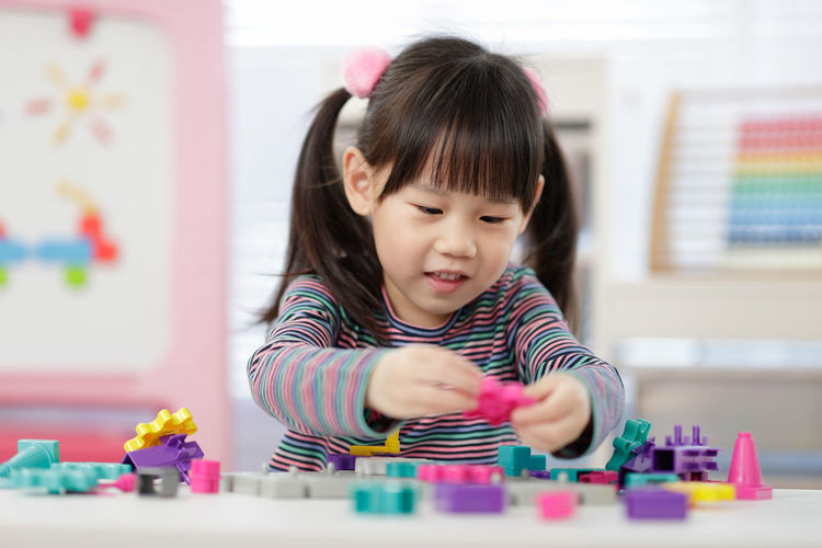 Cute girl playing with toy on table