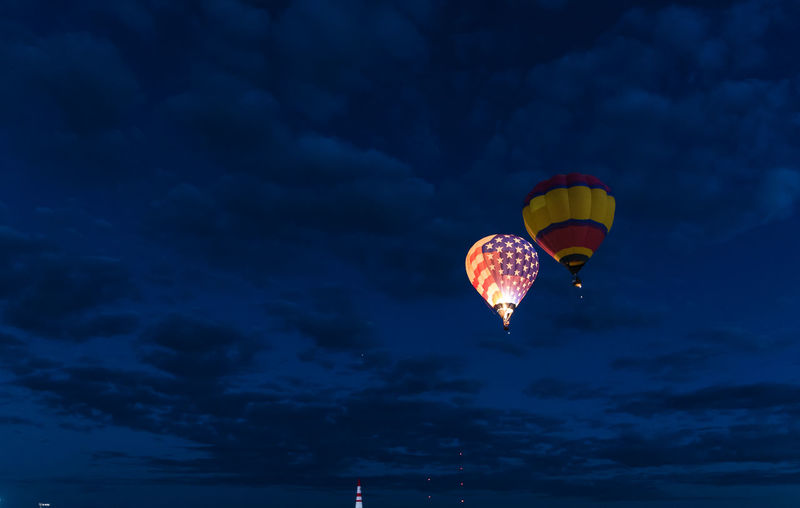 Low angle view of hot air balloons flying against sky at night
