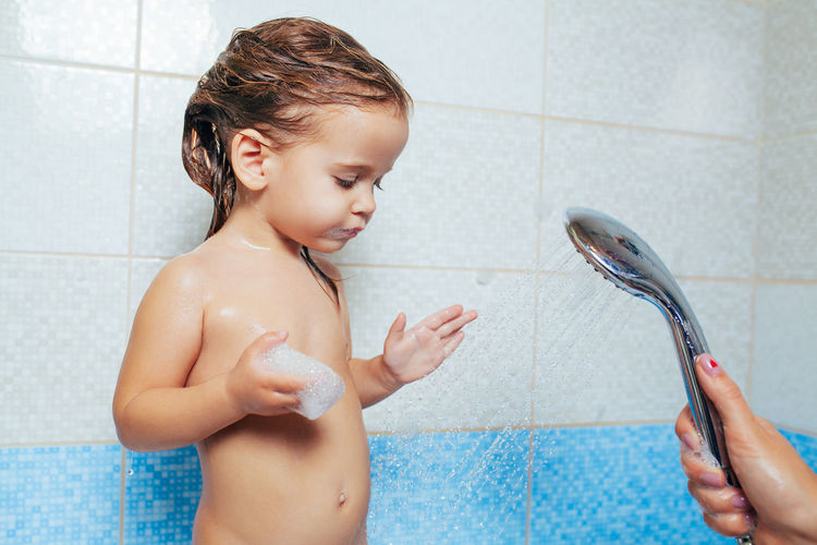 Cropped hands of mother bathing daughter in bathroom