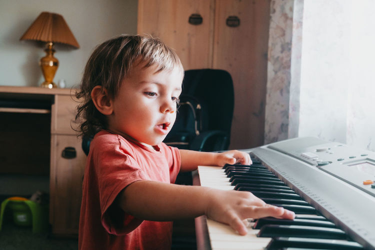 Cute boy playing piano at home