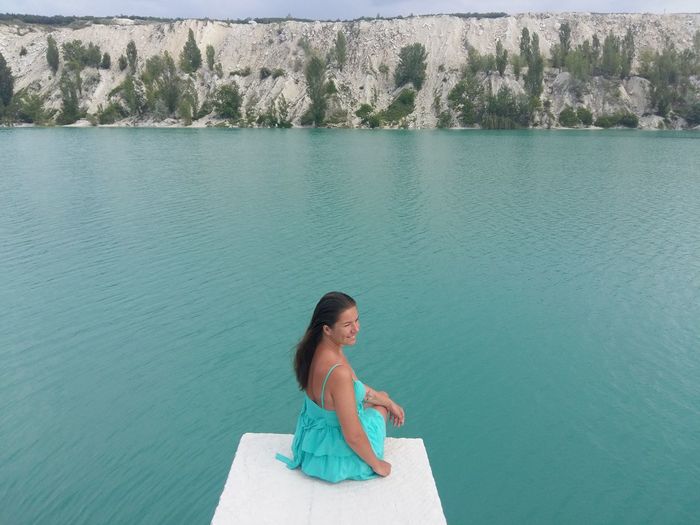 High angle view of woman sitting on diving platform against turquoise lake